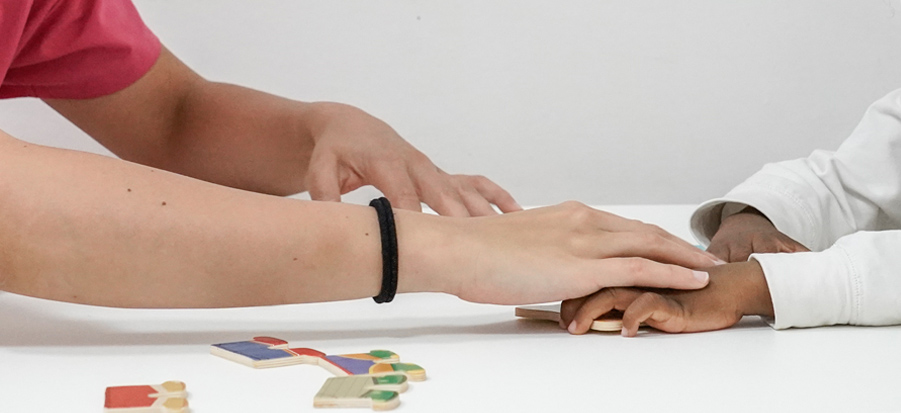 La mano della terapista guida la mano di una bambina durante l'attività terapeutica